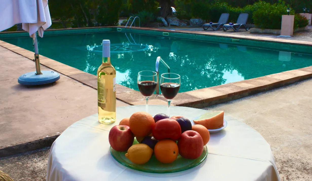 Copa de vino y fruta frente a la piscina