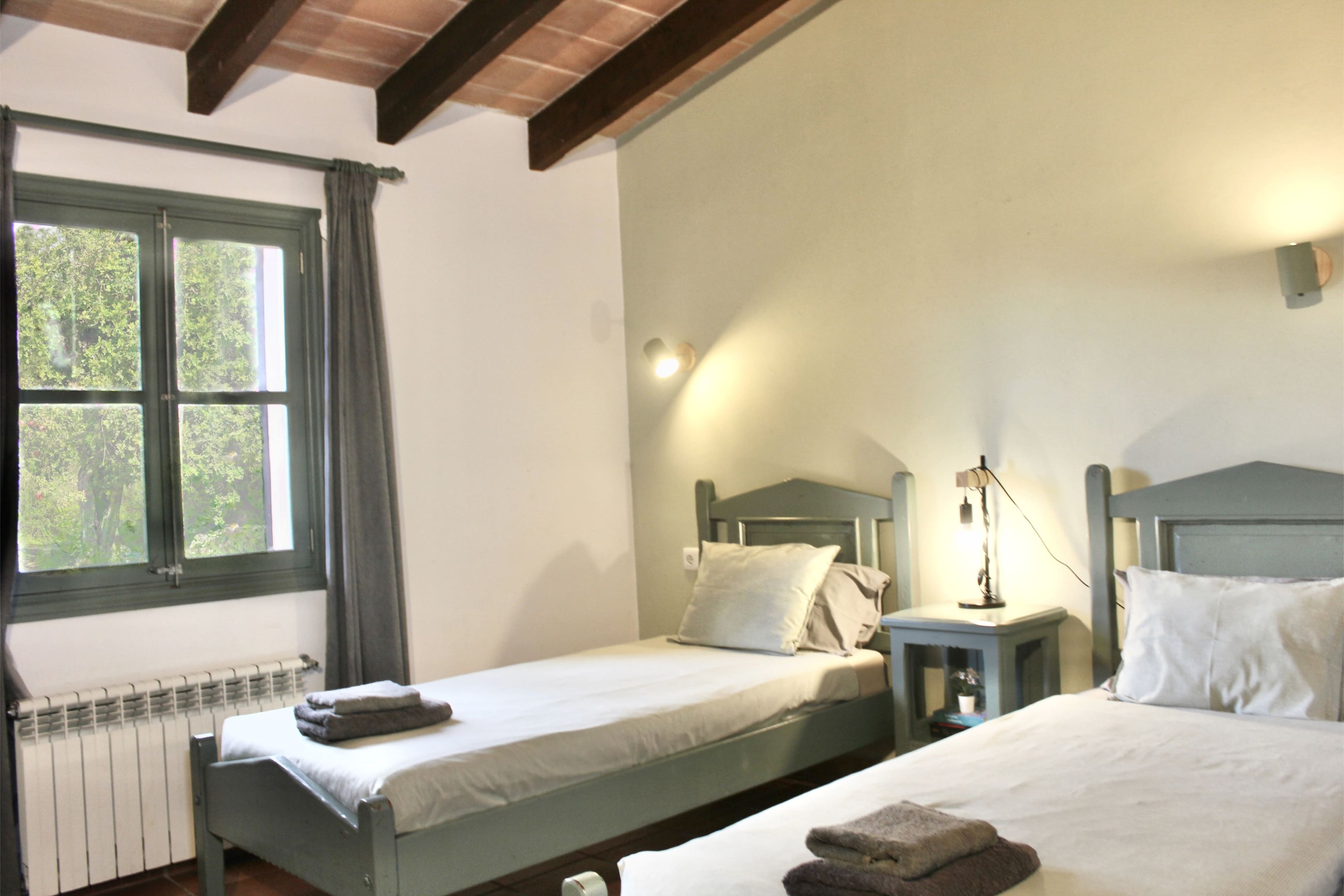 Habitación luminosa con camas individuales y vigas vistas